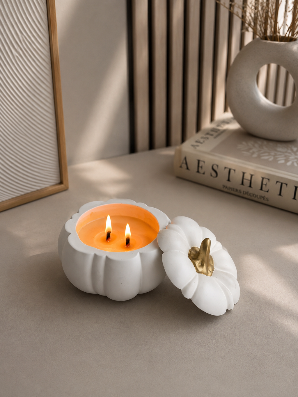 Lit pumpkin candle with double wooden wicks styled in a modern neutral interior