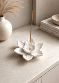 Handcrafted white daffodil flower incense holder with incense stick styled on a modern neutral stone entryway console.