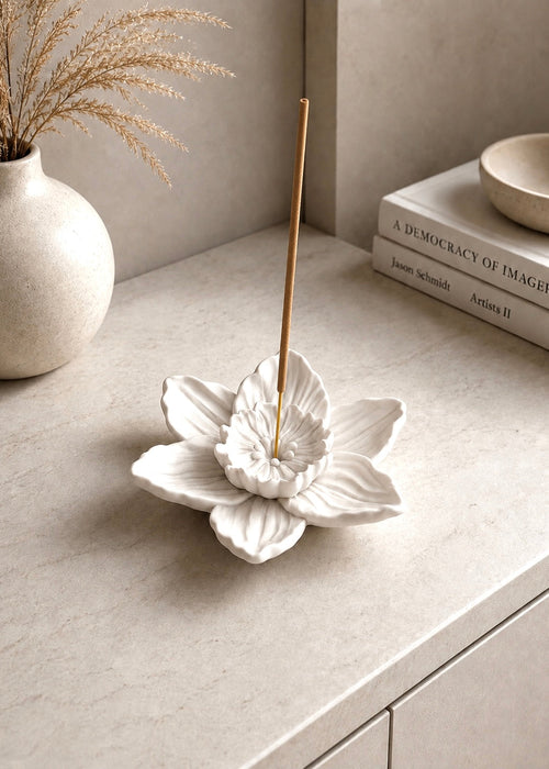 Handcrafted white daffodil flower incense holder with incense stick styled on a modern neutral stone entryway console.