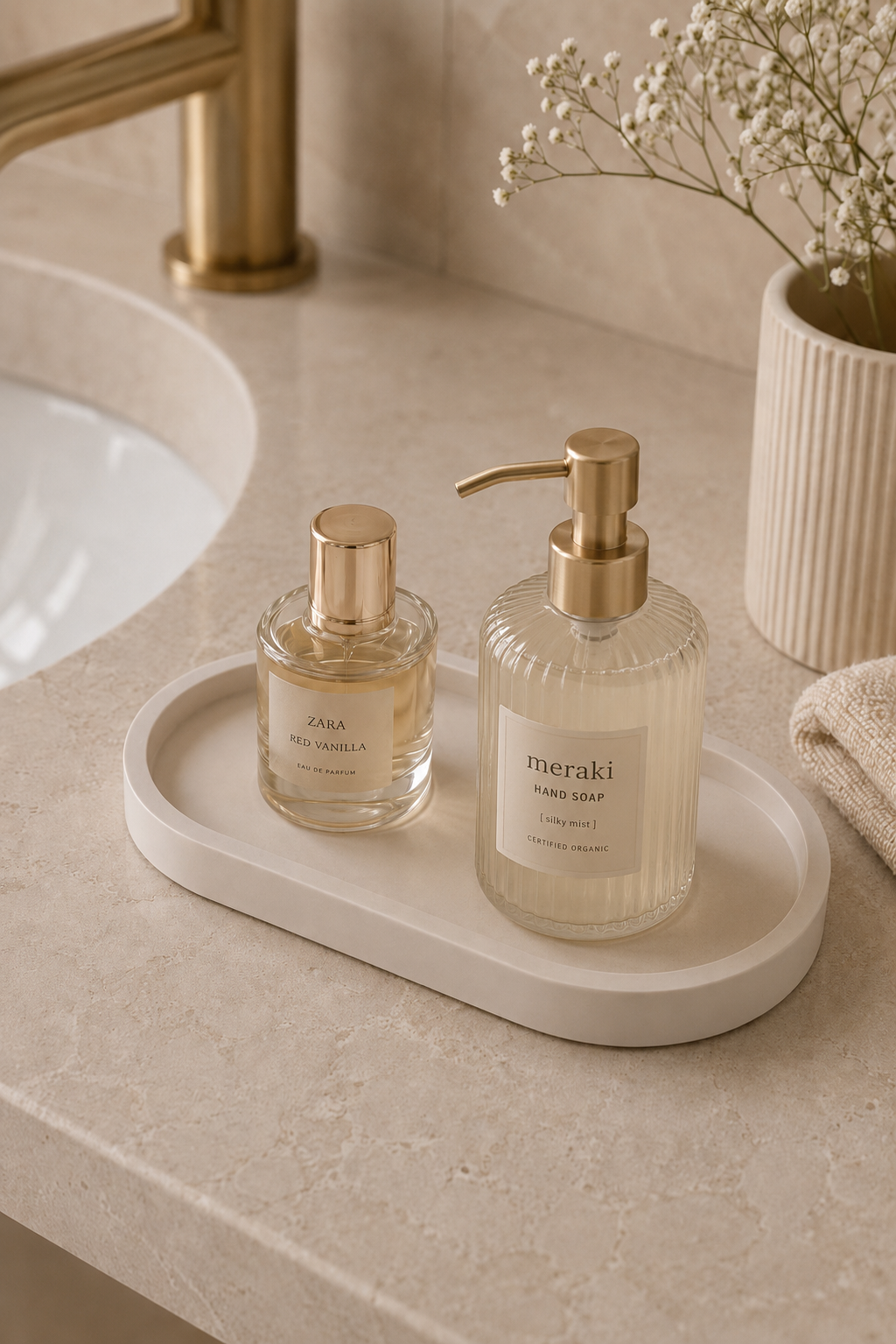 Minimalist oval vanity tray in soft white with luxury perfume bottle, gold bracelet and ring on a travertine stone table, neutral home decor by Odyssey Interior