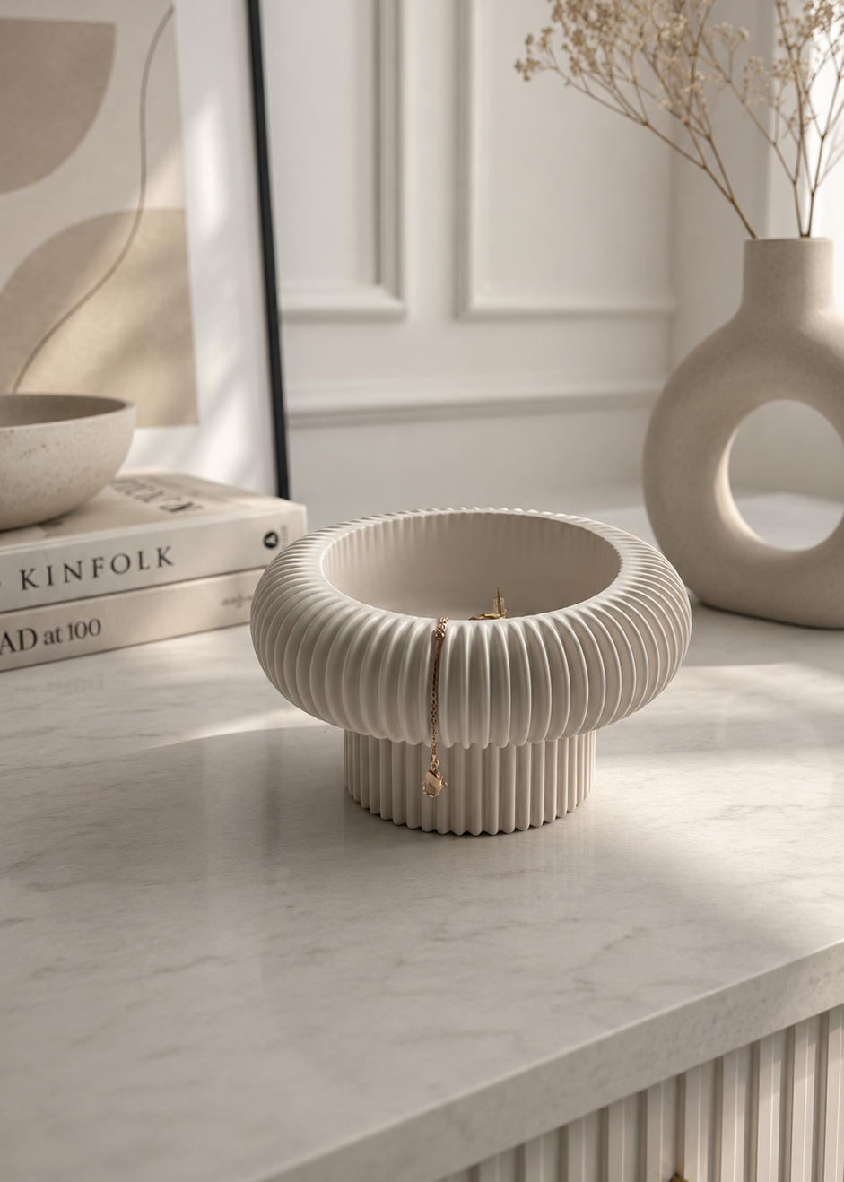 Handmade ribbed pedestal bowl crafted from Jesmonite, styled as neutral home decor with gold jewellery in a modern minimalist interior.