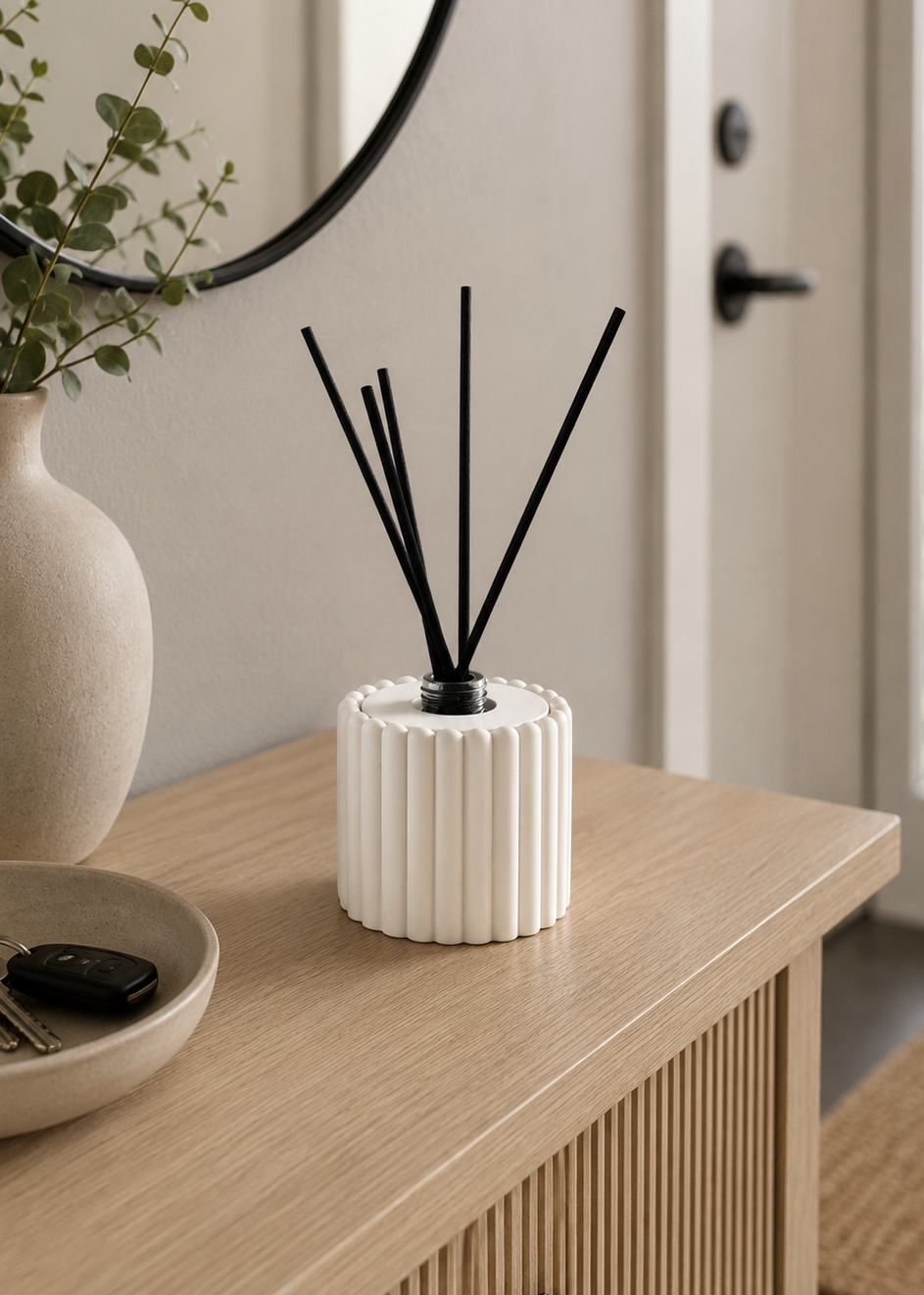 Handmade ribbed reed diffuser holder with glass bottle in white styled on a modern entryway console table with neutral home decor.