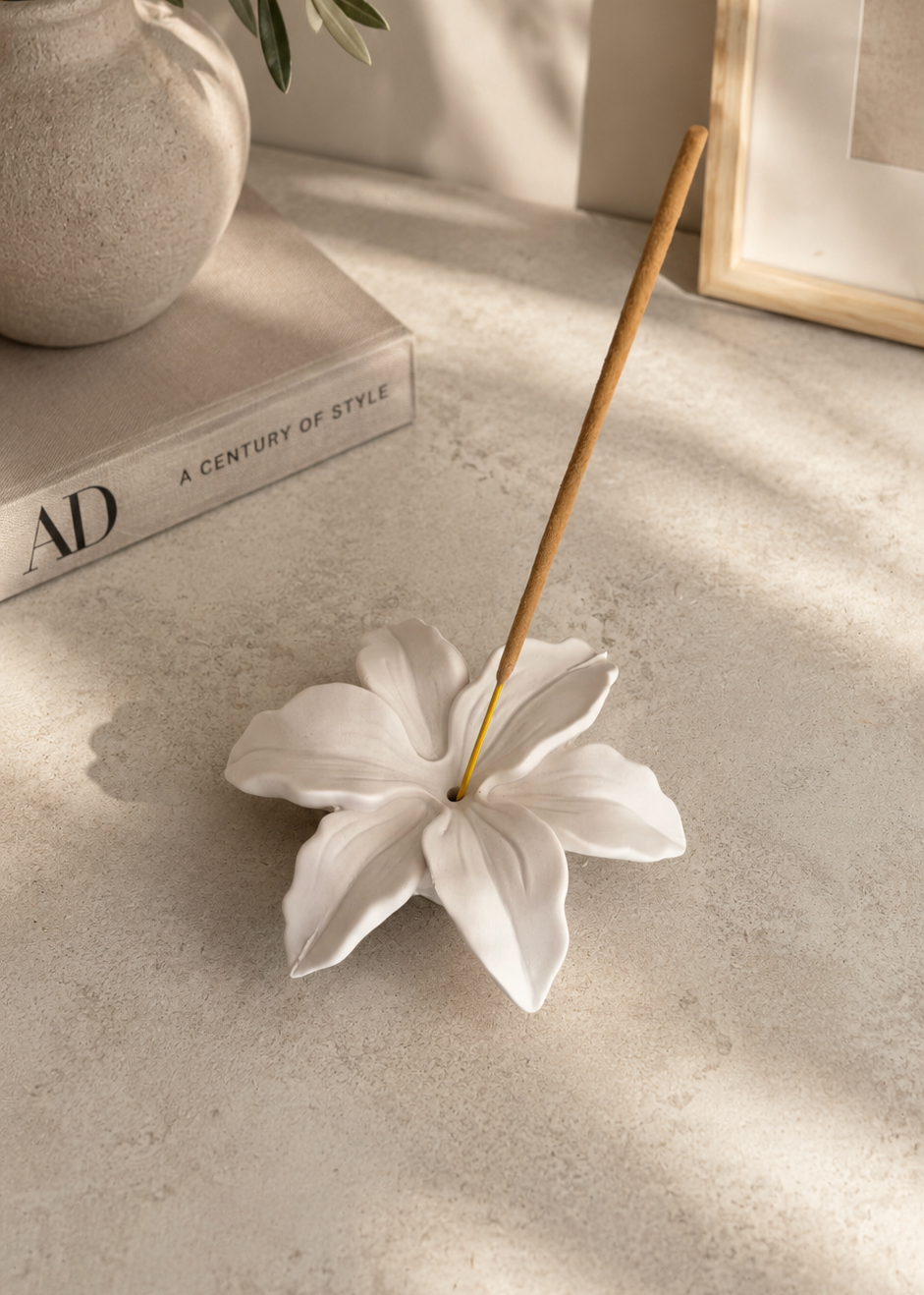 White Lily Flower Incense Holder styled on a decorative book in a modern neutral interior.